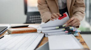 Businesswoman hands working on Stacks paper document files on her desk. Formation Premium : Comprendre les démarches administratives en France